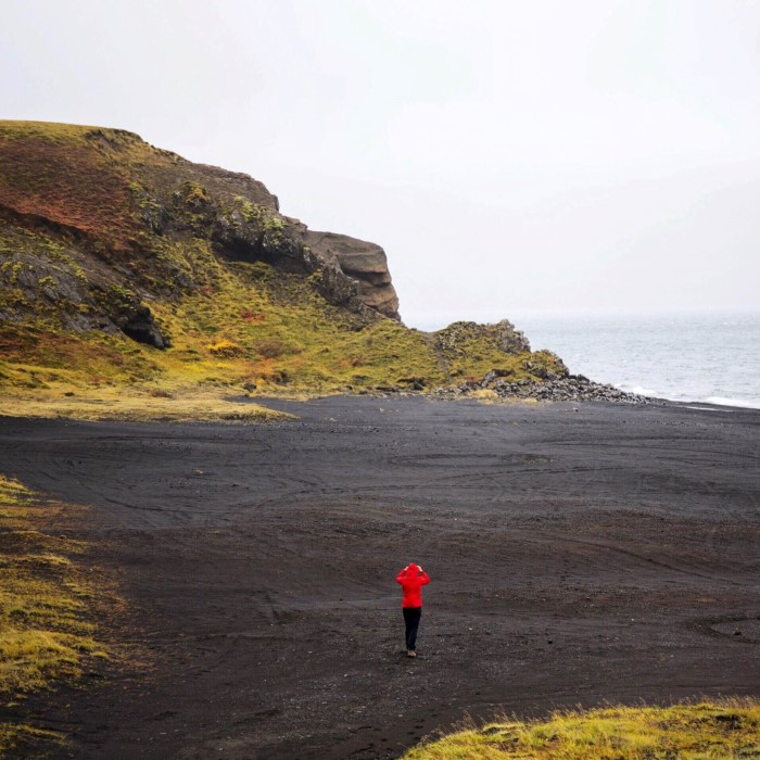 Woman walking over black sand beach Woman walking over black sand beach